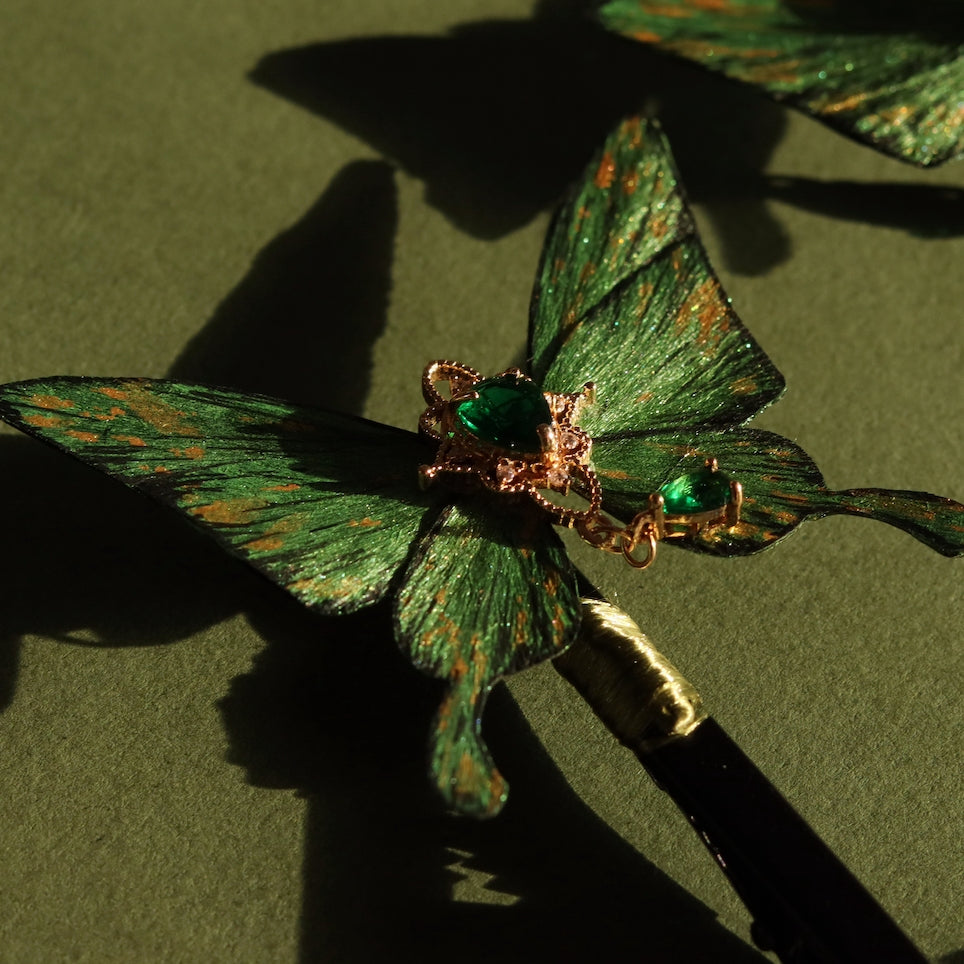 Handcrafted emerald green velvet butterfly accessory by Chujiu Mountain Atelier, featuring golden accents and a heart-shaped green crystal, offering versatility as a brooch, hair clip, or hairpin.