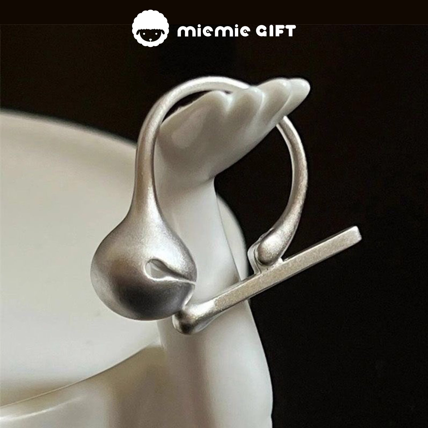 Close-up of the Wooden Fish Silver Ring elegantly displayed on a ceramic holder, showcasing its minimalist 925 sterling silver design and functional wooden fish mallet, ideal for stress relief and mindfulness, by MieMie Gift.